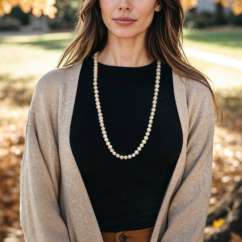 Cultured pearl necklace worn outdoors, long strand of round white pearls