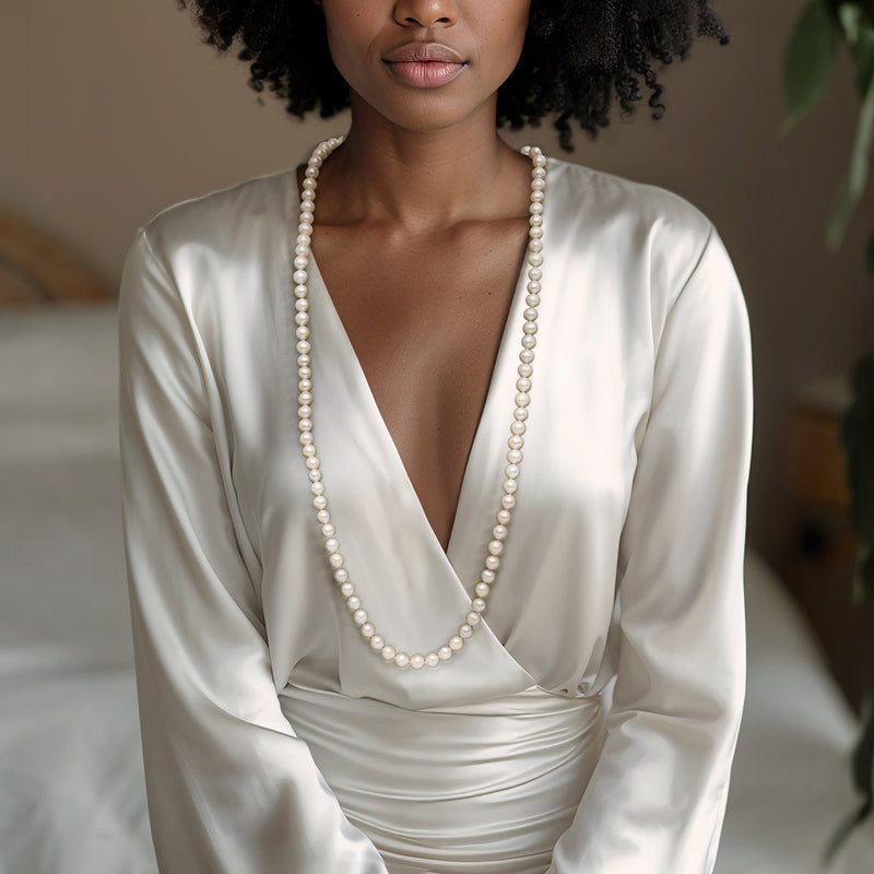 Cultured pearl necklace on white satin dress, long strand of round white pearls