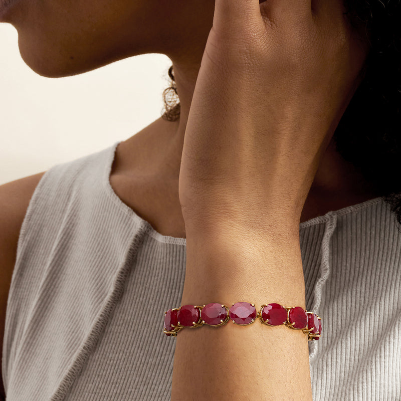 Ruby-style gemstone bracelet on wrist with oval red stones and gold clasp