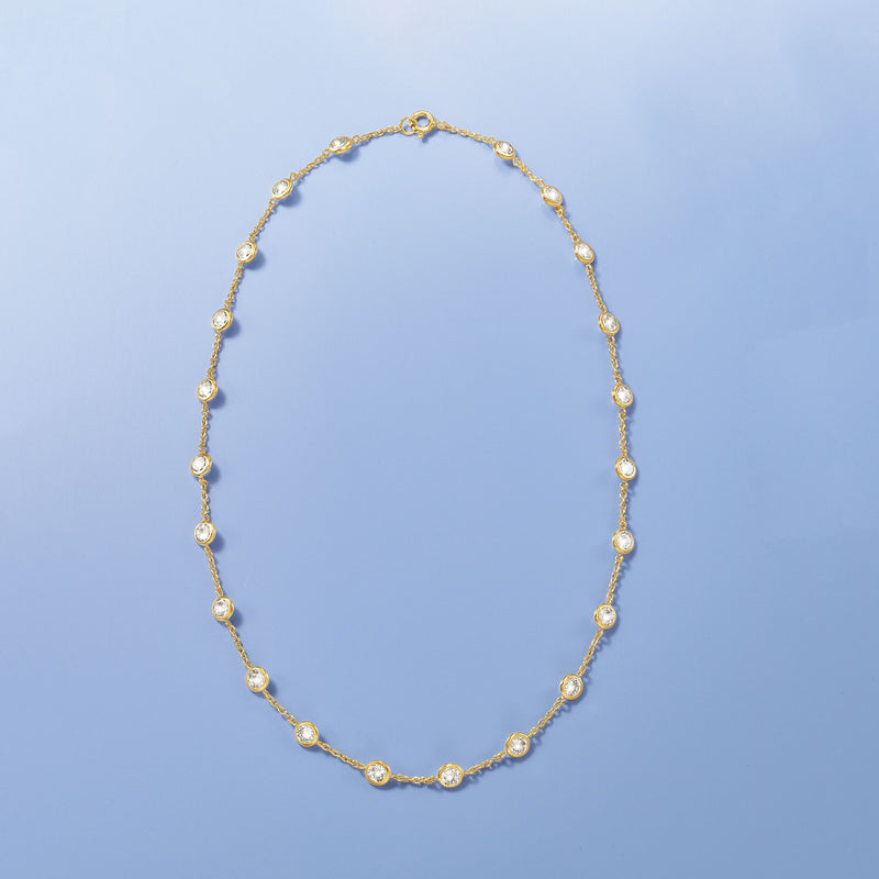 Isolated gold-tone CZ station necklace with round bezel-set stones on a delicate chain