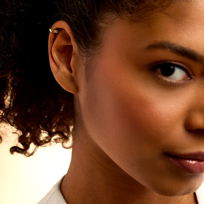 Polished 14kt yellow gold ear cuff worn on ear, open band profile