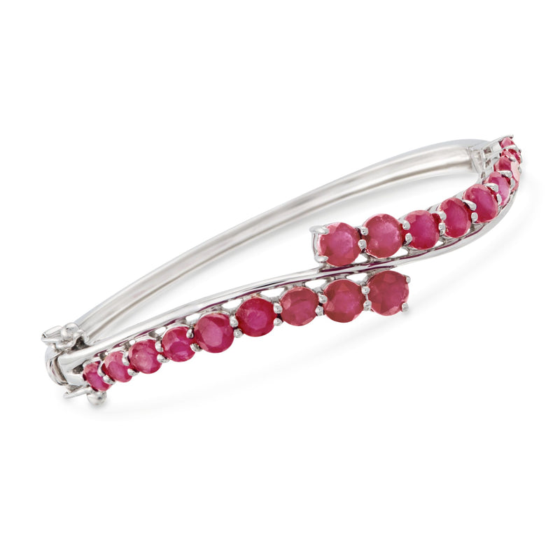 Sterling silver bypass bangle with ruby-red gemstones in a curved setting