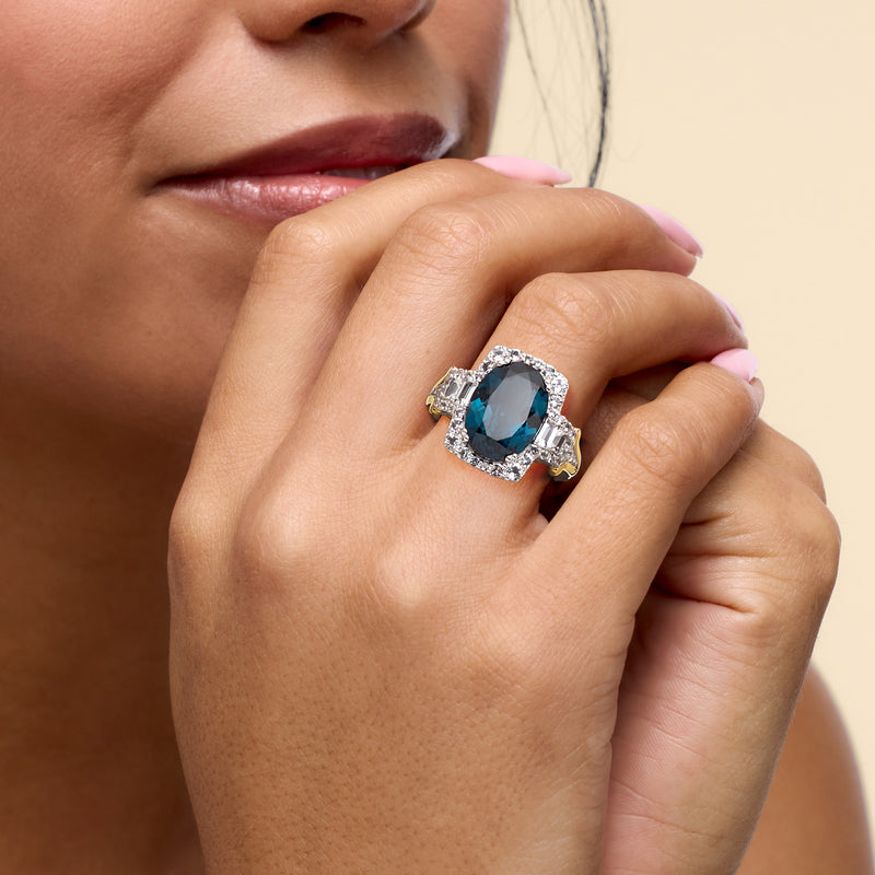 Two-tone sterling silver ring on finger with oval London blue topaz and white stone halo