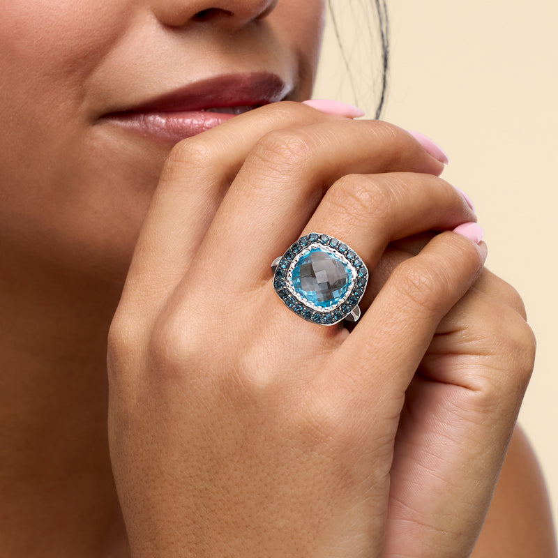Sky-blue topaz ring on hand with round blue gemstone halo in sterling silver band