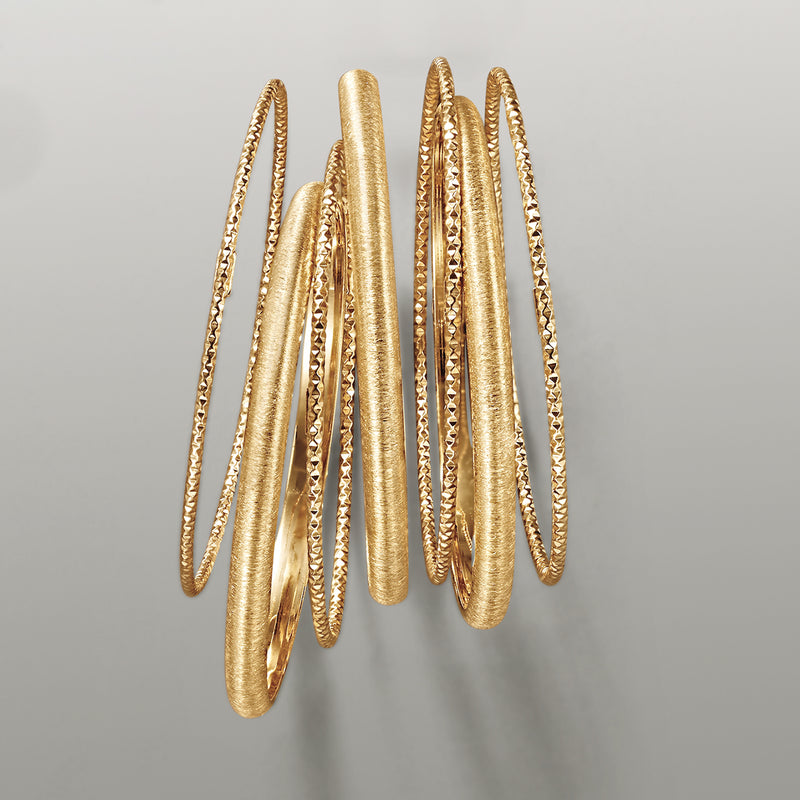Seven gold over sterling silver bangles with mixed textured and smooth surfaces