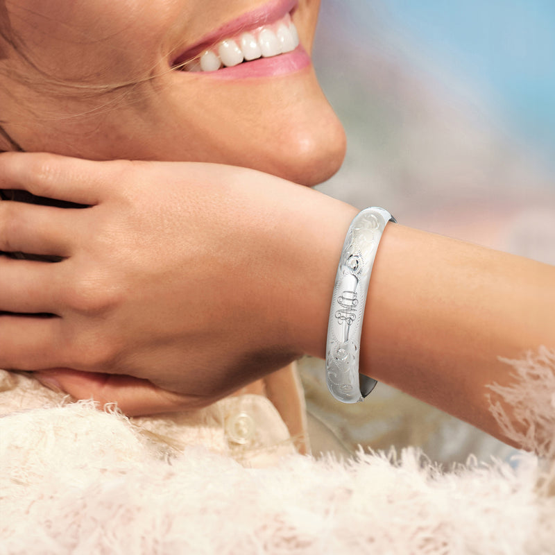 Sterling silver bangle bracelet with engraved scrollwork, worn on wrist