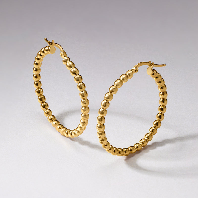 Gold beaded hoop earrings, angled view of textured round bead hoops with post closures