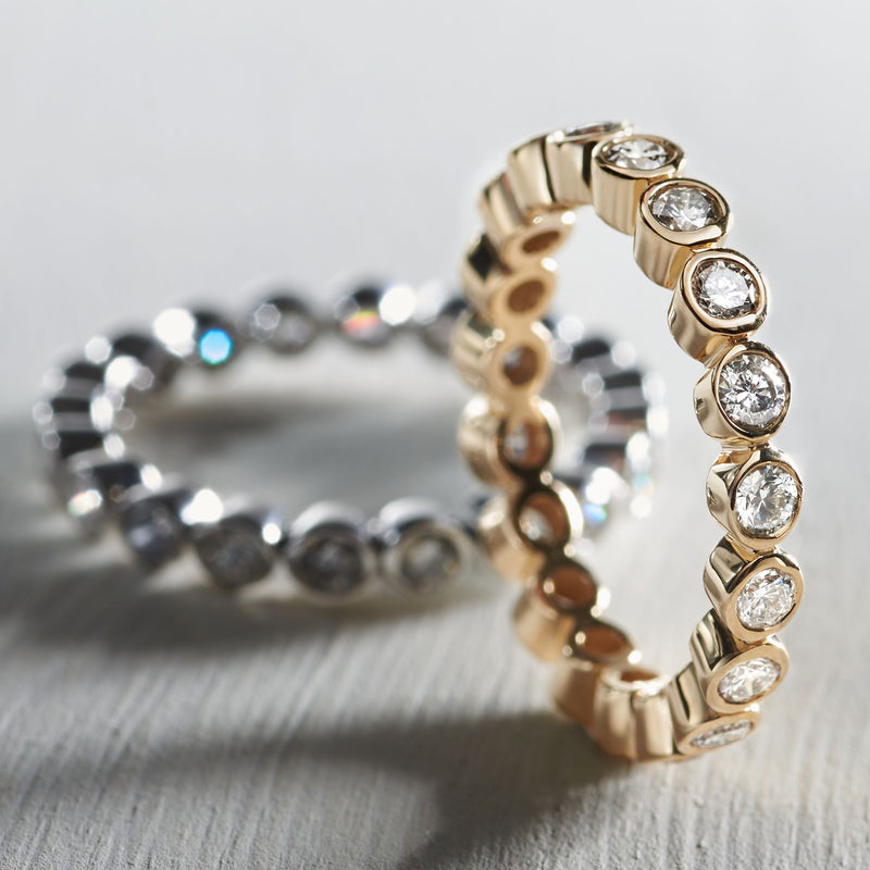 14kt yellow gold diamond eternity band angled close-up, bezel-set round diamonds