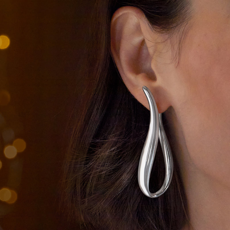 Twisted sterling silver U-shaped hoop earrings on ear, polished curved hoops