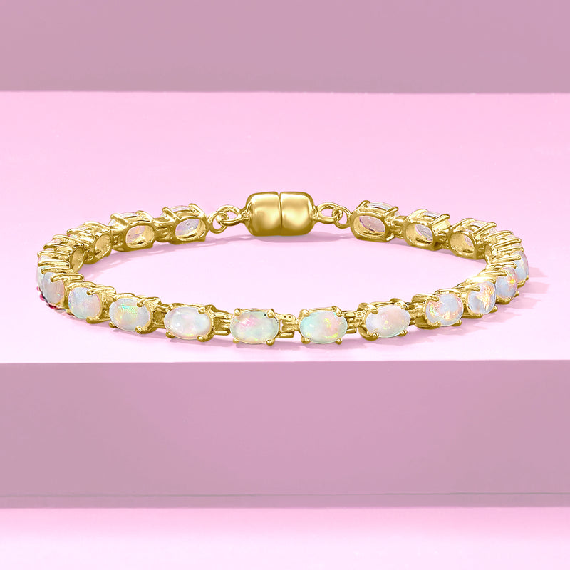 Gold tennis bracelet with central barrel clasp and oval opal-like stones