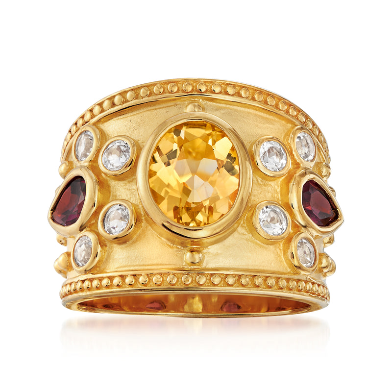 Gold-tone ring with oval citrine center, round white stones, and dark red side gems