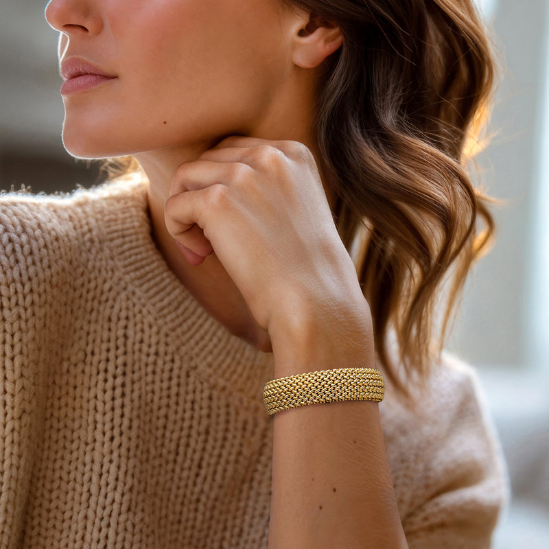 Wide yellow gold link bracelet on wrist with rounded textured mesh links