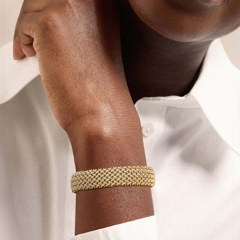 Yellow gold riso-link bracelet worn on wrist, woven chain with clasp