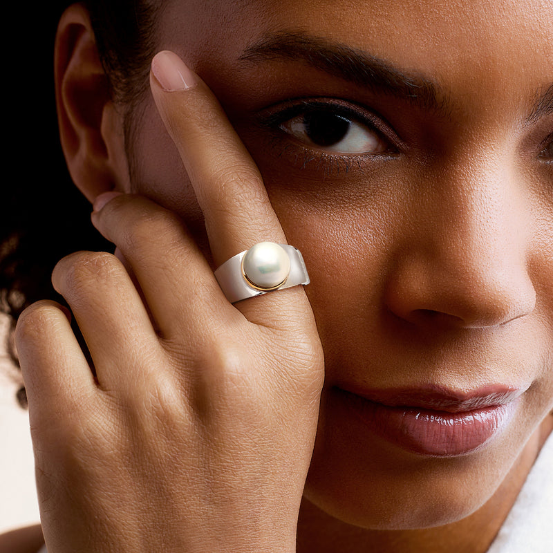 Cultured pearl ring on finger in sterling silver with gold bezel, close-up