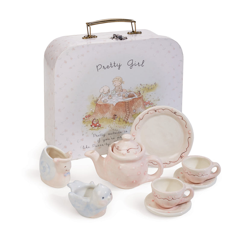 Ceramic tea set with pink teapot, blue cups, saucers, and serving pieces in tin