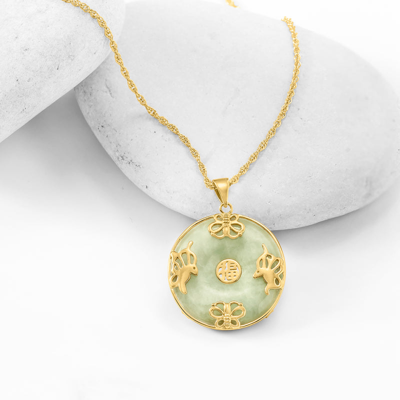 Gold pendant necklace with round jade disc, butterfly cutouts, and floral charm