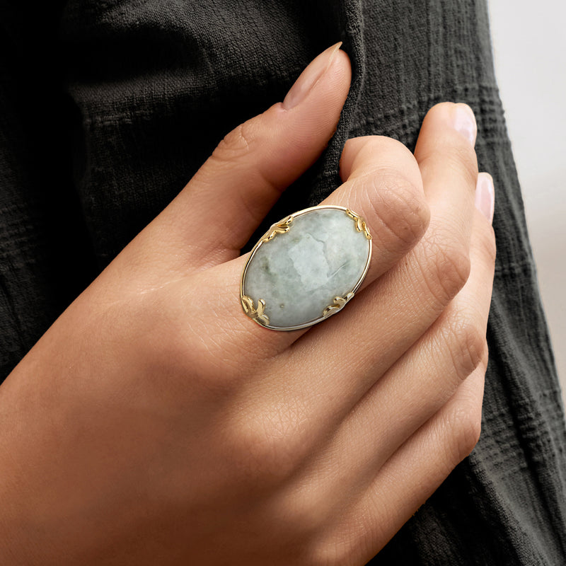 Jade oval ring on finger, gold-tone bezel with leaf-like side details