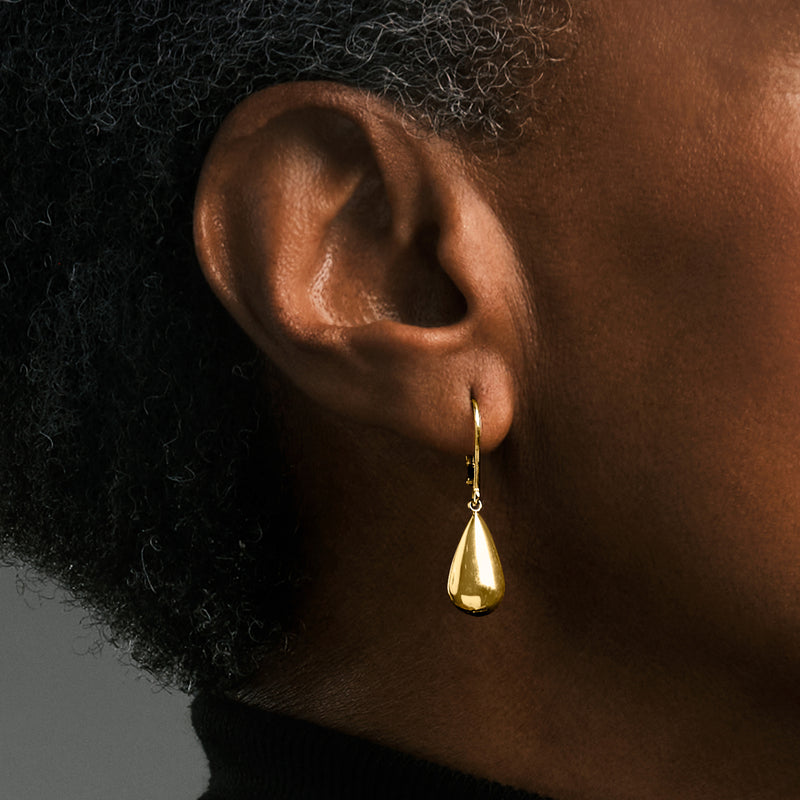 Gold teardrop leverback earring worn on ear, polished drop