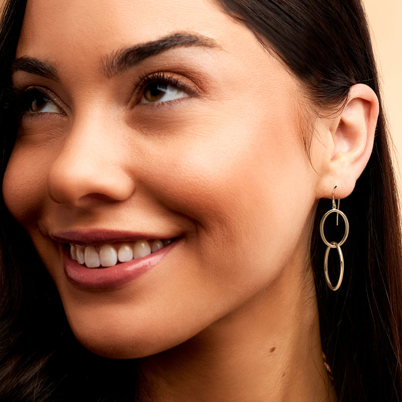 Yellow gold double-oval drop earrings on ear with oval links