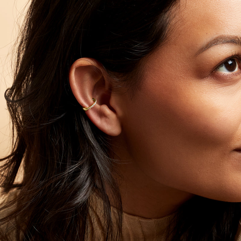 Diamond single ear cuff in 14kt yellow gold on ear, curved with small stones