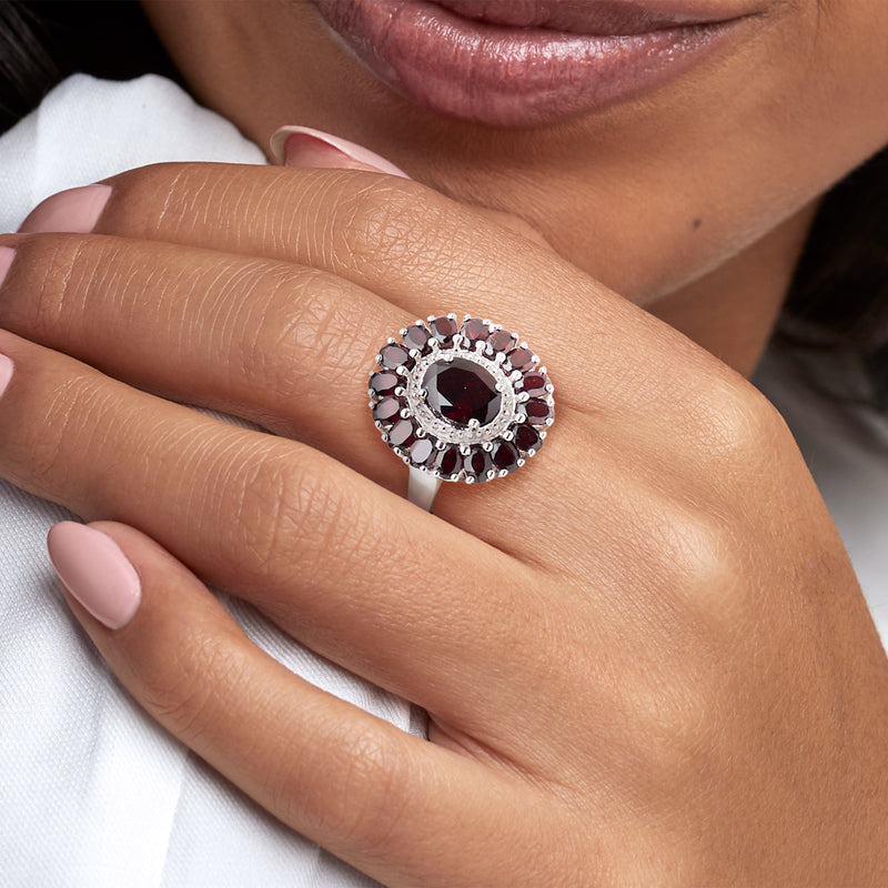 Sterling silver garnet ring on finger, oval center with dark red halo stones