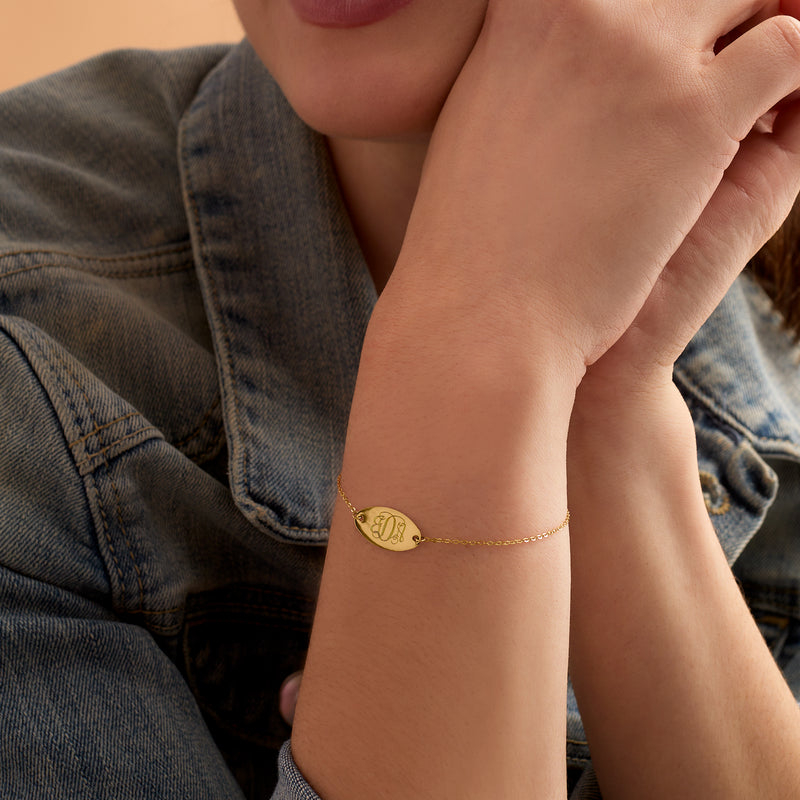 14kt yellow gold oval disc personalized bracelet on wrist with engraved initials