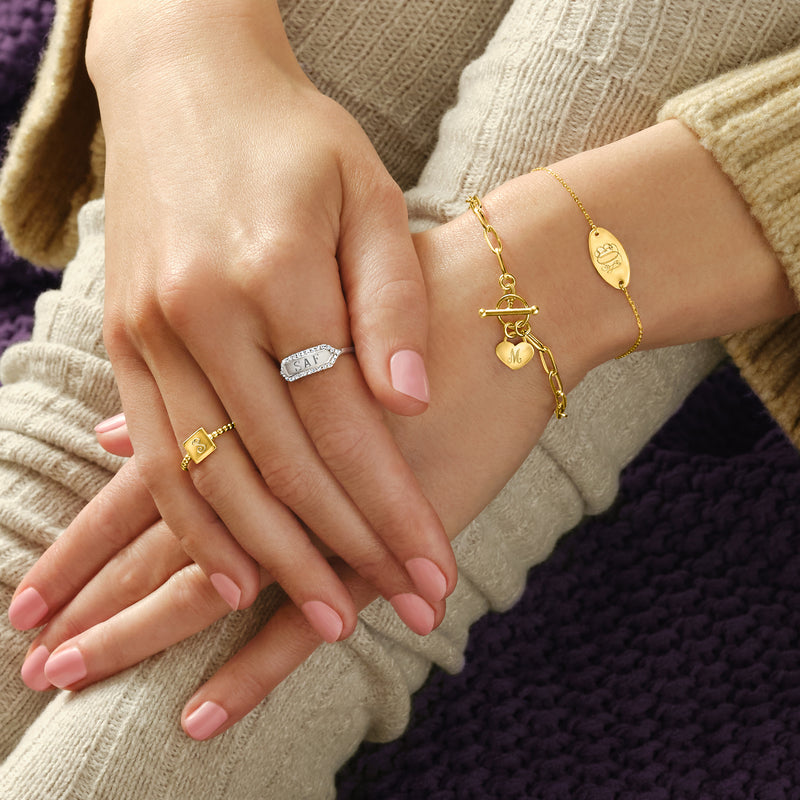 14kt yellow gold oval disc bracelet with engraved initials, worn on wrist