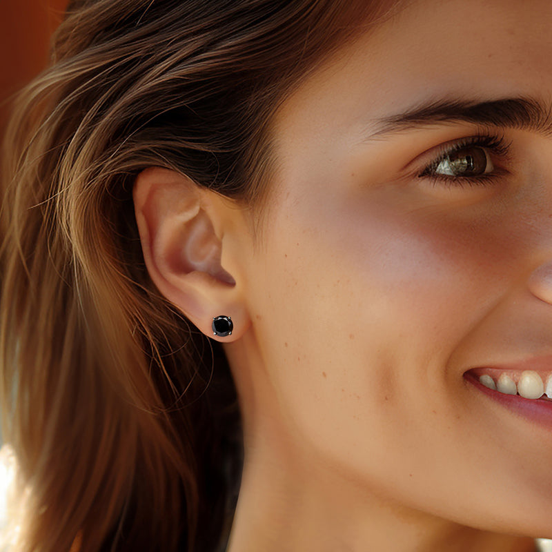 Black diamond stud earrings on ear, round faceted black stone with white gold prong setting