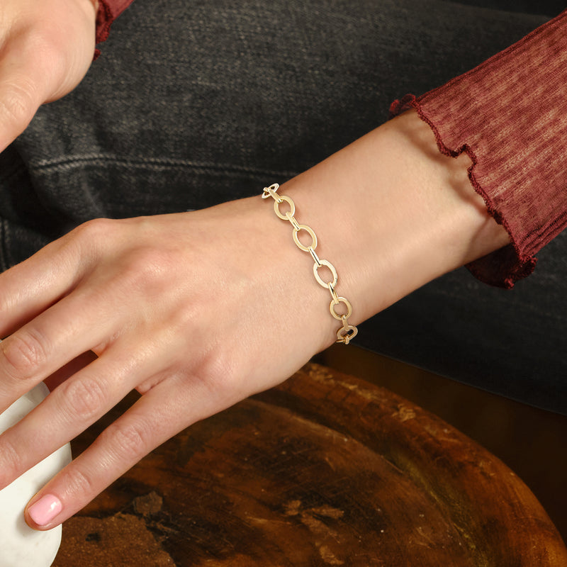 Yellow gold oval-link bracelet on wrist with flat oval links and clasp