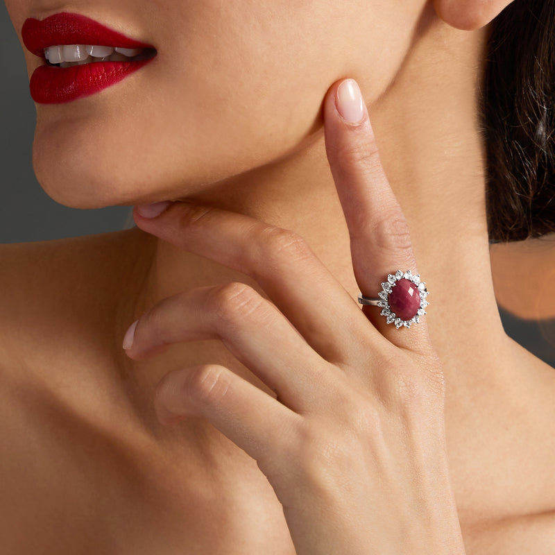 Ruby-like red gemstone halo ring on finger; sterling silver band with small clear stones