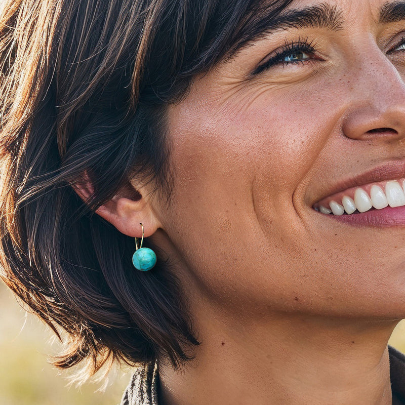Turquoise button drop earrings in 14kt yellow gold, shown on ear