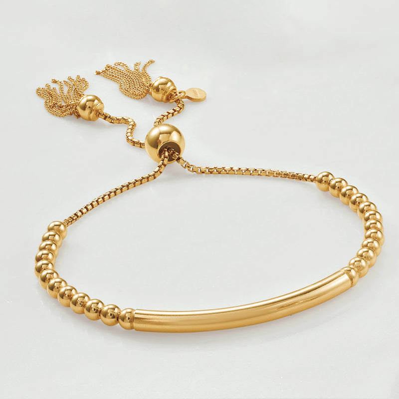 Gold bead bolo bracelet with smooth bar and textured tassel knot details