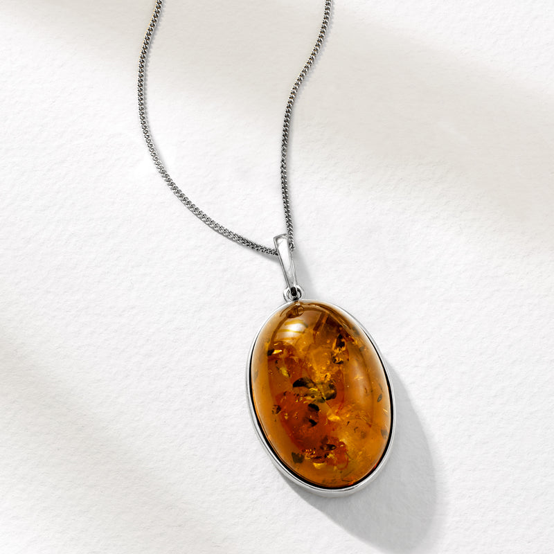 Oval amber pendant on sterling silver necklace chain with oval metal frame