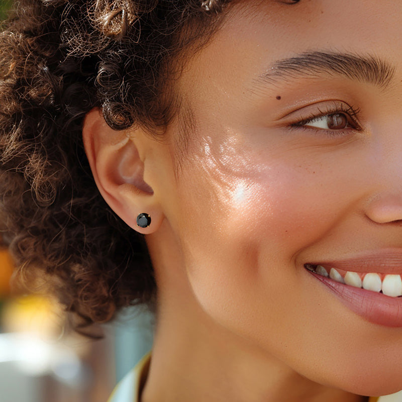 Black diamond stud earring on ear, round center with yellow gold post
