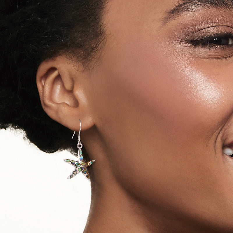 Sterling silver starfish drop earrings with iridescent inlay shown on model's ear