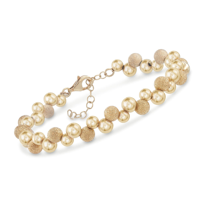 Gold bead bracelet with pearl-like spheres, textured accents, and lobster clasp.