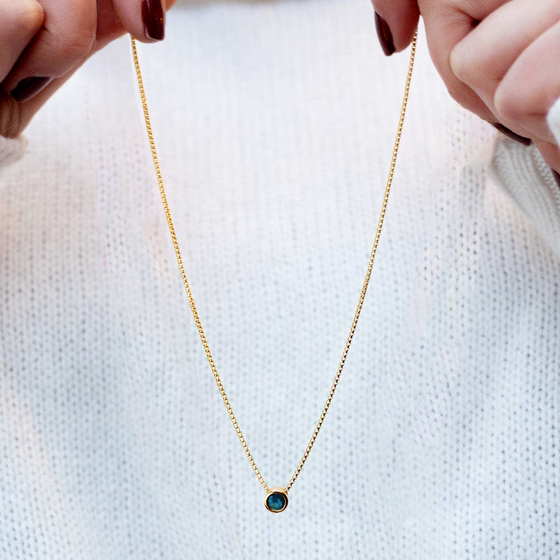 Gold-tone necklace with round blue bezel pendant on fine link chain