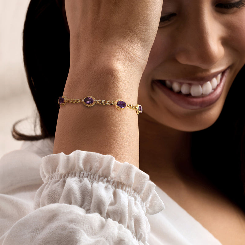 Amethyst link bracelet on wrist with purple oval stones and gold chain links