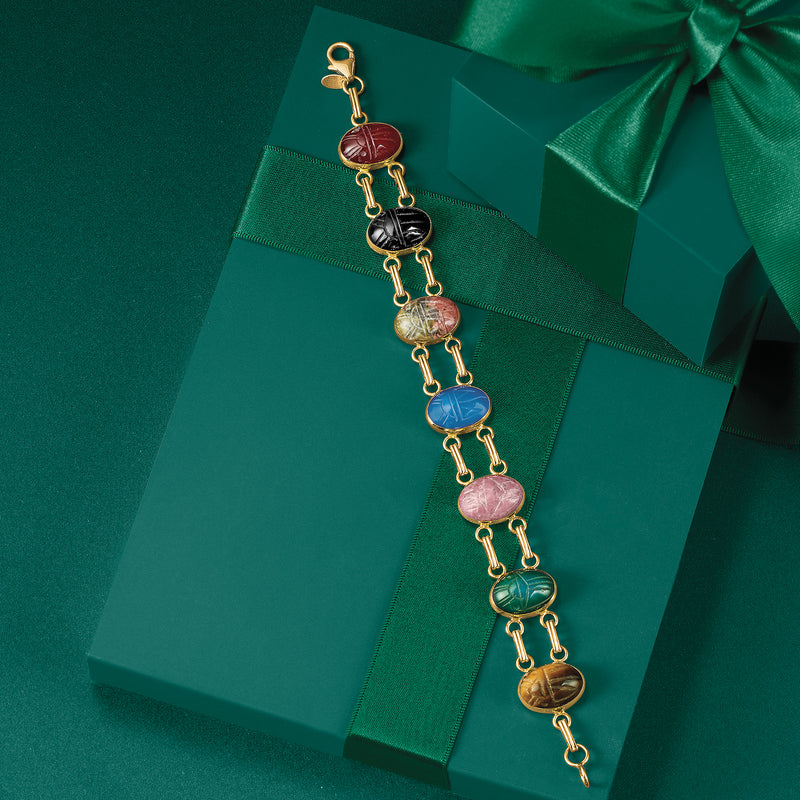 Yellow gold charm bracelet with red, blue, and pink oval stones on a chain