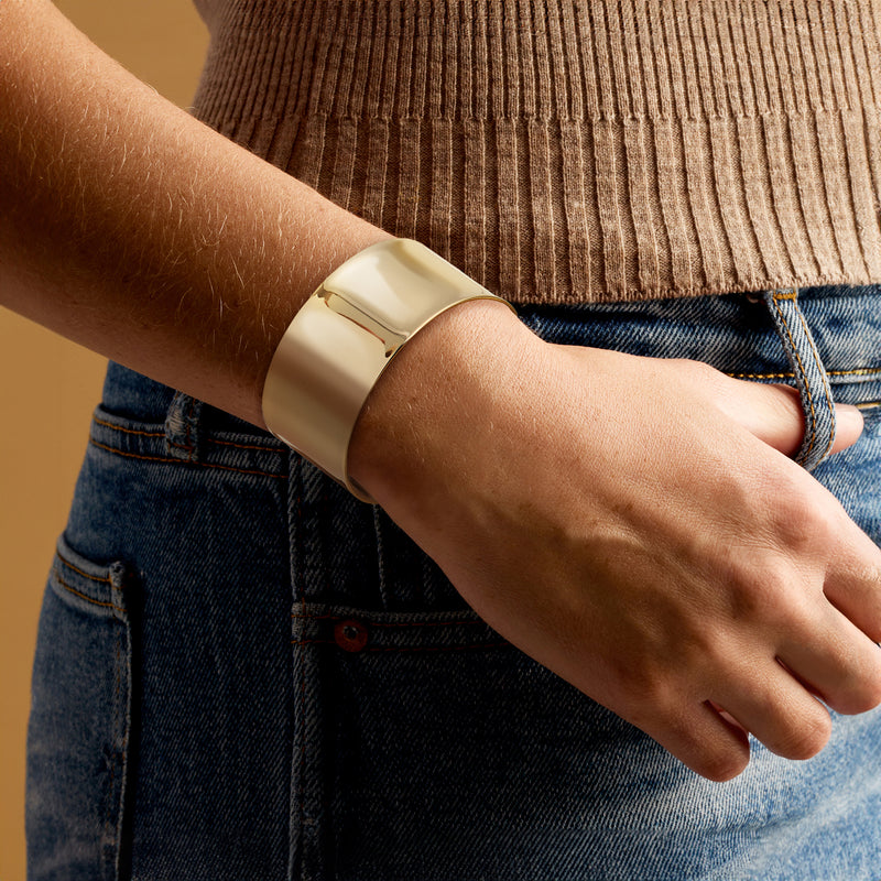 14kt yellow gold wide cuff bracelet on wrist, polished smooth open cuff