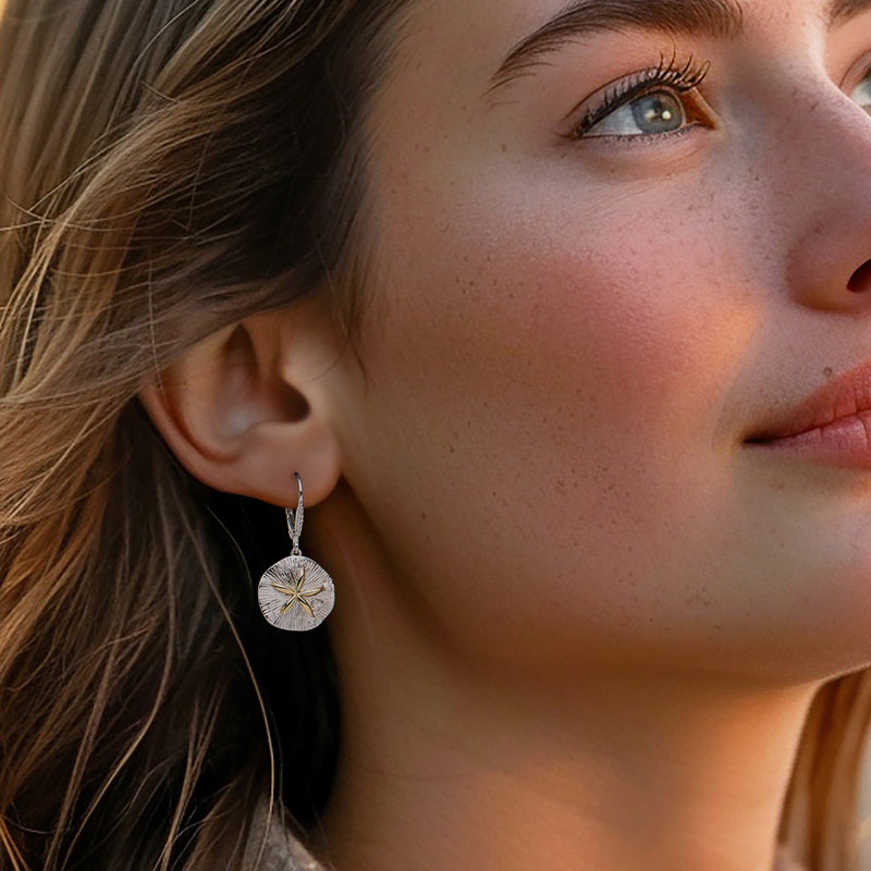 Sand dollar drop earrings on model: sterling silver round disc with gold star and clear stones