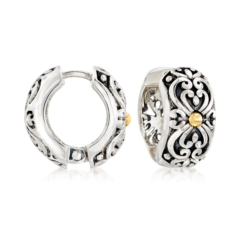 Silver huggie hoop earrings with ornate scrollwork and small yellow-gold center.