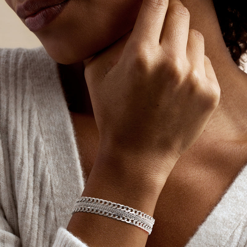 Sterling silver curb-link bracelet worn on wrist, layered chain look