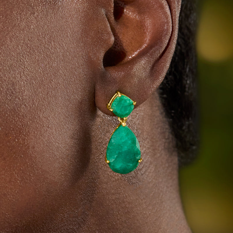 Emerald drop earrings on ear, emerald-green pear-shaped drops in gold-tone setting