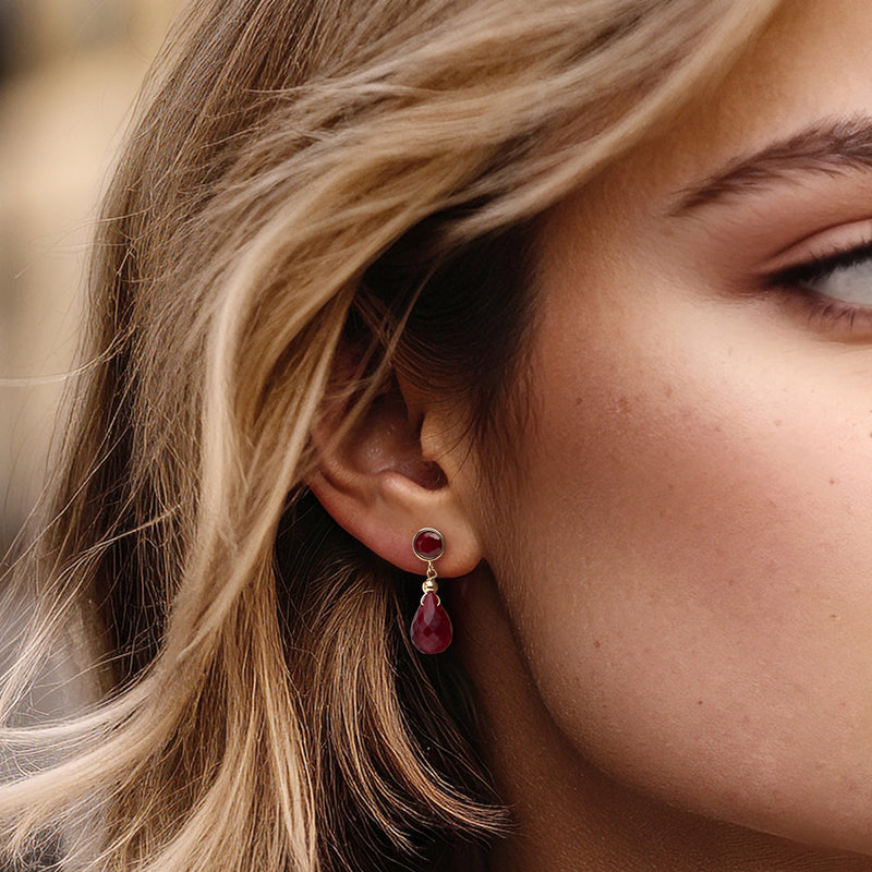Ruby drop earrings in 14kt yellow gold on model ear, red teardrop ruby dangle