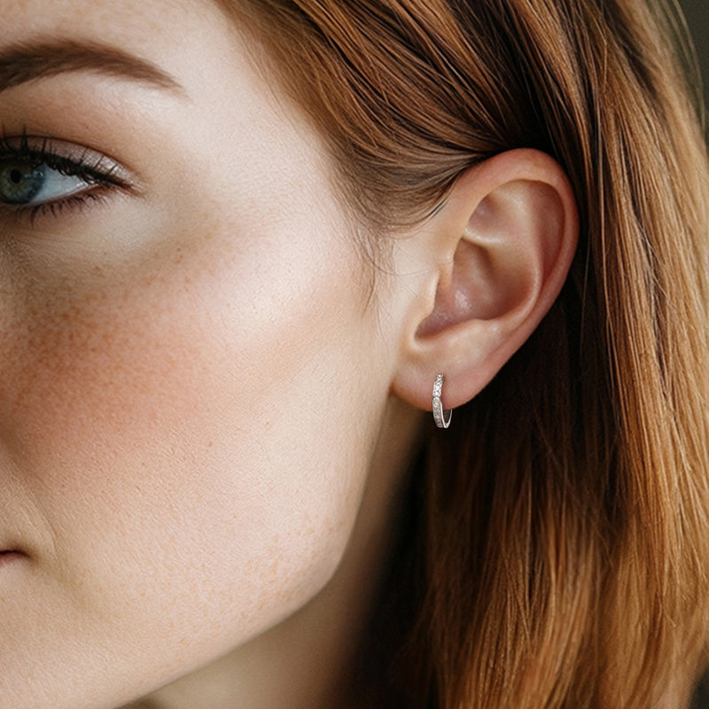 Diamond huggie hoop earring in white gold on a model's ear