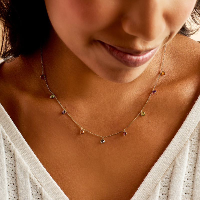 14kt yellow gold station necklace worn close-up, bezel-set multicolor round gems
