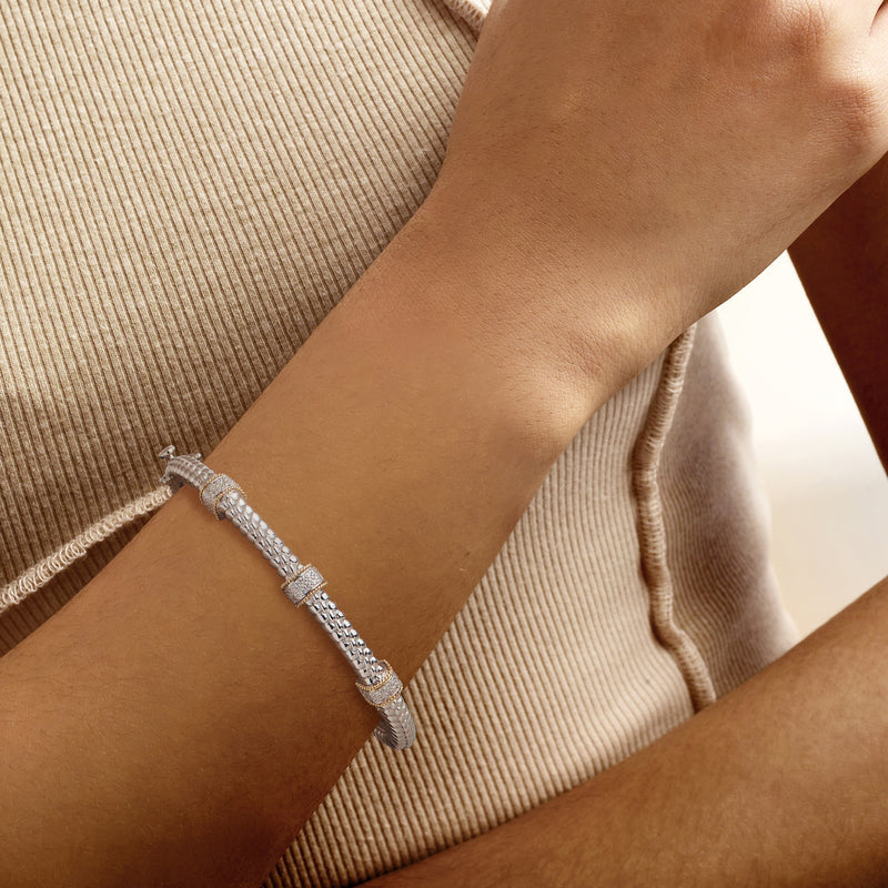 Sterling silver diamond station bangle bracelet with yellow gold stations, worn on wrist
