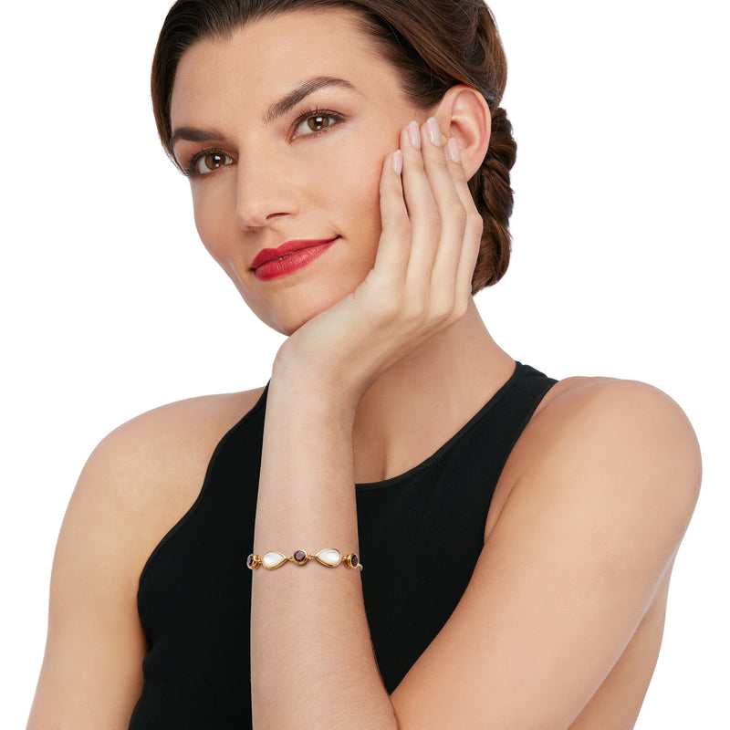 Gold bolo bracelet with mother-of-pearl oval and red garnet beads on wrist