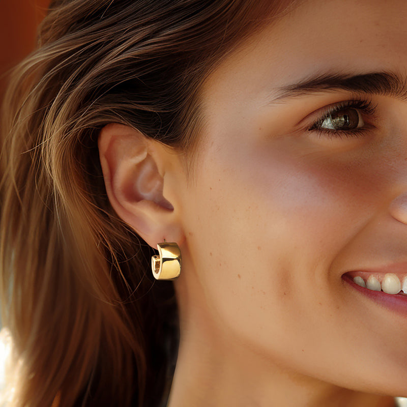 18kt yellow gold huggie hoop earring on ear, polished rounded ring